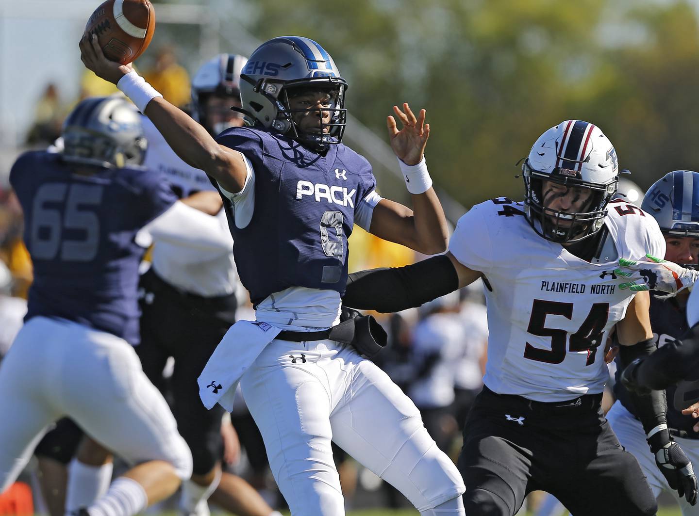 Oswego East's Tre Jones attempts to get rid of the ball as Palinfield North's Justin Yeazell bears down on him during the varsity football game between Plainfield North and Oswego East on Saturday, October 23, 2021 at Oswego East high school in Oswego, IL.