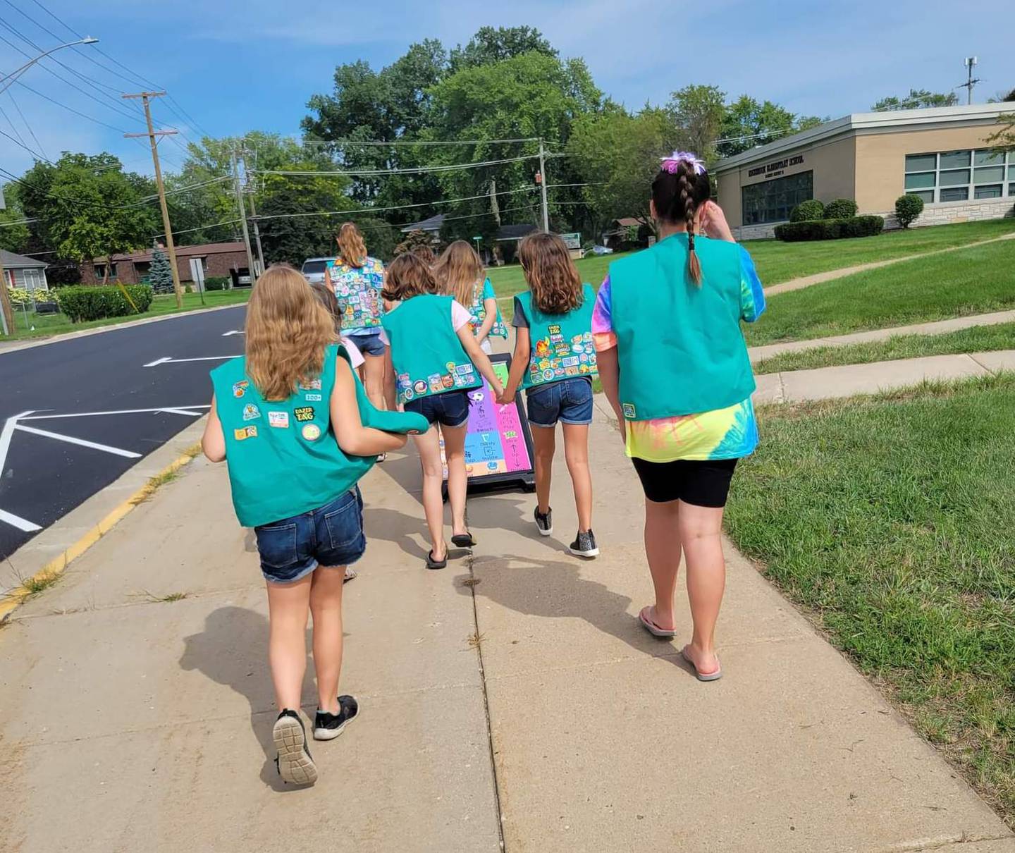 Girl Scouts from McHenry Troop 360 roll the A-frame communications signs to each of the two playgrounds at Edgebrook Elementary School on Monday, Aug. 15, 2022.