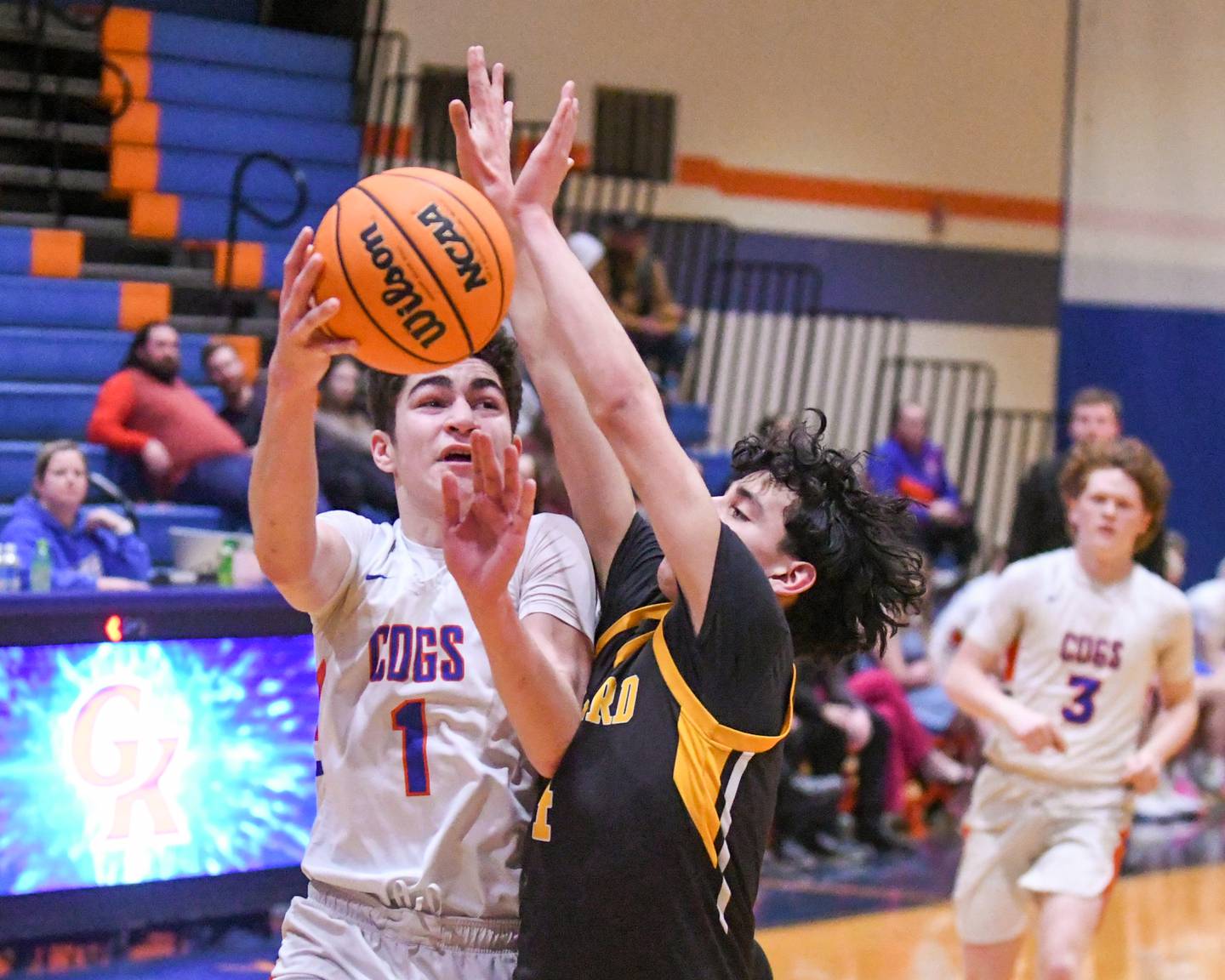 Genoa-Kingston's Marcus Johnson (1) makes a shot while being fouled by Harvard's Julian Acosta (4) during the game on Thursday Feb. 13, 2025, held at Genoa-Kingston High School.