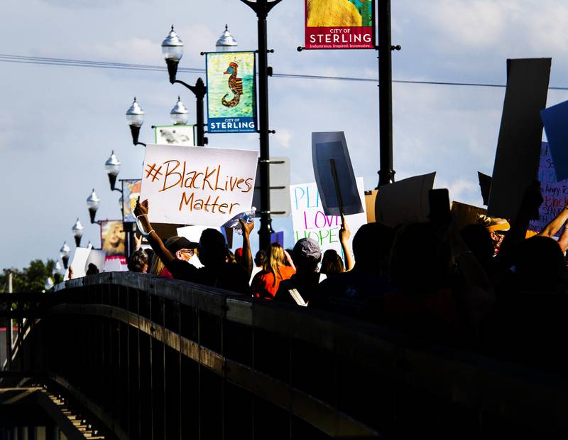 A ray of sun lights up a Black Lives Matter sign as protesters march across the First Avenue Bridge from Sterling to Rock Falls. A few hundred protesters took to the streets Friday to protest the death of George Floyd while in police custody on May 25.