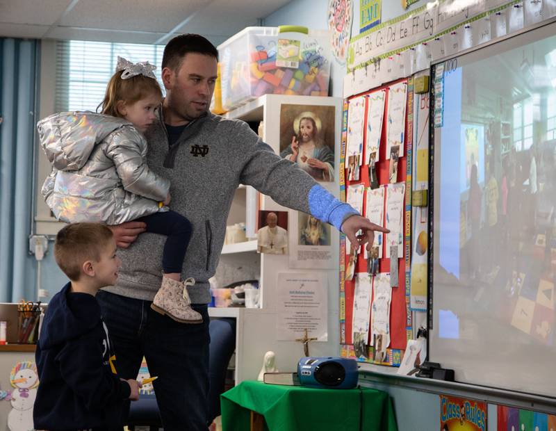 Nolan, left, Chloe, middle and Ryan Winiarski look at photos on the whiteboard of Nolan’s Kindergarten class during Saint Mary of Gostyn School's Open House in Downers Grove  on Sunday, Jan. 29, 2023.