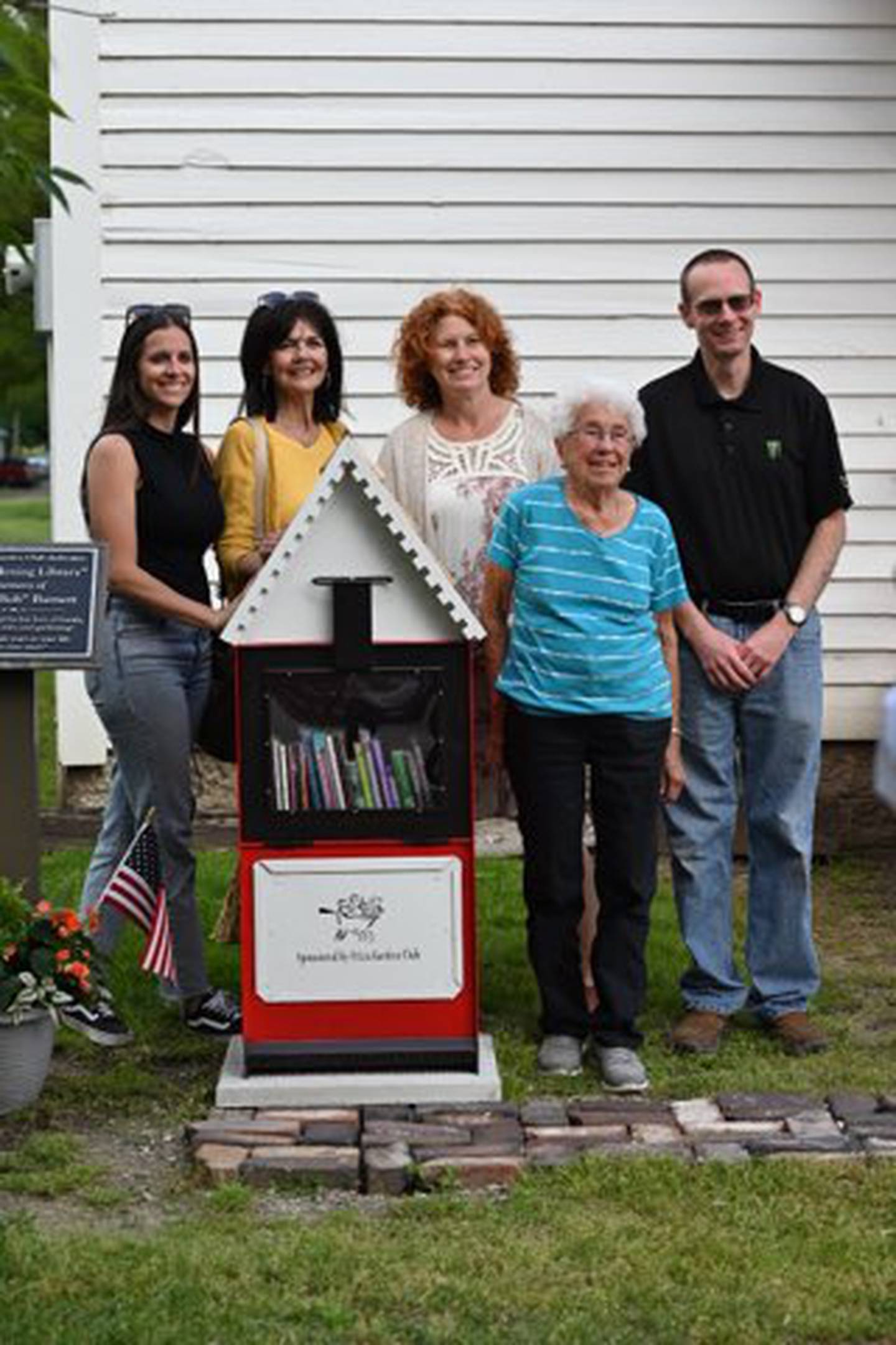 Dolores Barnett (second from right) stands next to the little library honoring her and her late husband Bob Barnett, longtime supporters of the Utica Garden Club, at a dedication Thursday, May 16, 2024, outside the one-room schoolhouse managed by the La Salle County Historical Society. From left are village trustees Kylie Mattioda and Debbie Krizel, director of village affairs Jamie Turczyn and Mayor David Stewart.