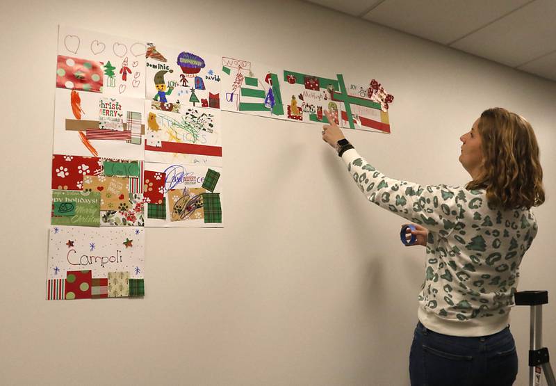 Julie Kemblowski hangs up family quilt pieces Friday, Dec. 2, 2022, during the Very Merry Huntley Holiday Open House at the Huntley Area Public Library. The event featured musical entertainment by Andy Huber, reindeer, Santa, a scavenger hunt, face painting, and a snowball toss.