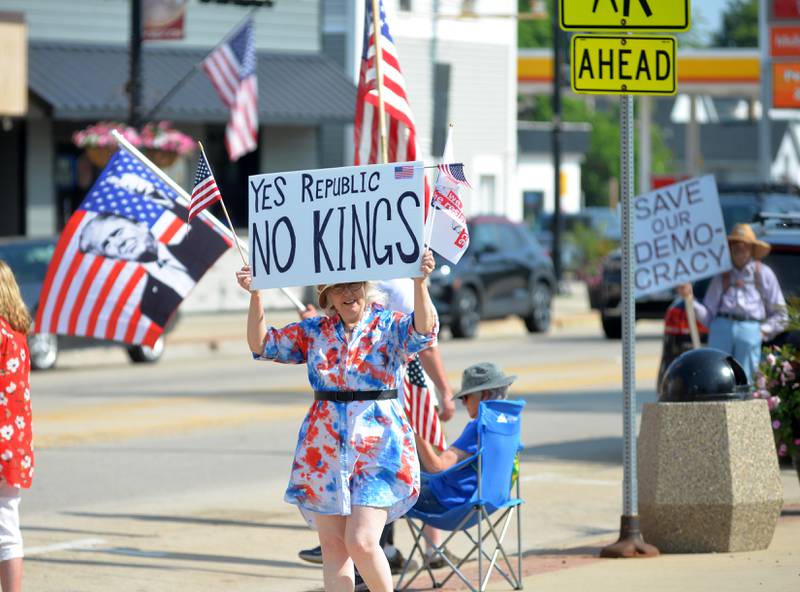 Attendees at the "No Kings" and a counter "Flag Day" carry their signs and flags in Oregon, Illinois on Saturday, June 14, 2025.