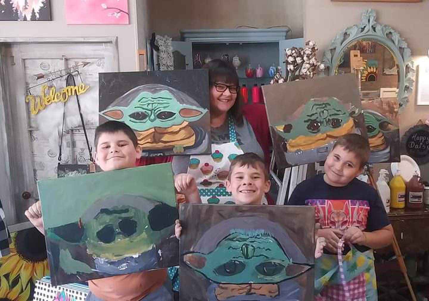 Braycin Hiller, Amanda Hiller, Barrett Hiller, and Bryer Hiller hold up their Baby Yoda paintings.