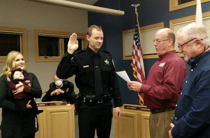 Tyler Lobdell takes the oath as the Yorkville Police Department's newest patrol officer on Dec. 14. Mayor John Purcell administers the oath, as Lobdell's wife Mallory looks on, holding the couple's baby Monroe. At right is Yorkville Board of Fire and Police Commissioners Chairman Robert Johnson. (Mark Foster - mfsoter@shawmedia.com)