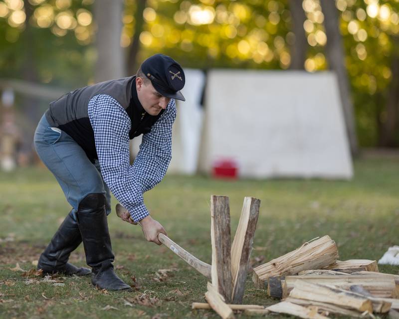 A soldier chops firewood to burn while camping overnight at the Shadows Of The Blue and Gray Civil War reenactment at City County Park on October 10, 2025 in Princeton.
