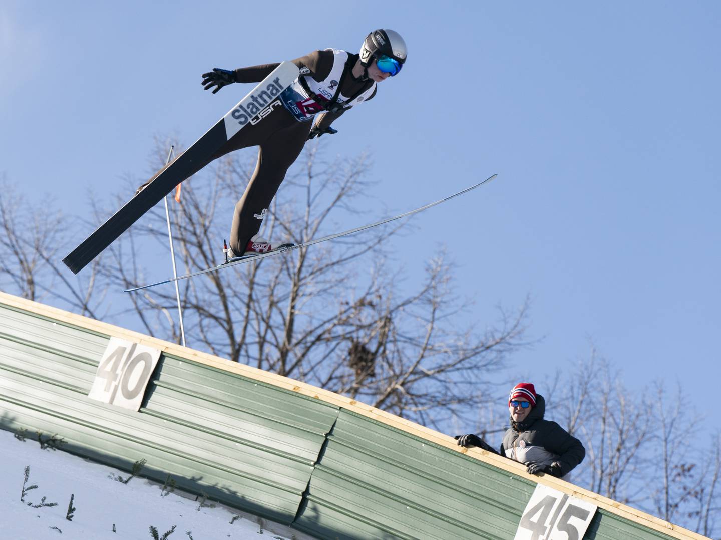 Norge Ski Club's Isak Nichols flies through the air as a judge watches during the Norge Annual Winter Ski Jump Tournament on Sunday, January 26, 2025 at the Norge Ski Jump in Fox River Grove.