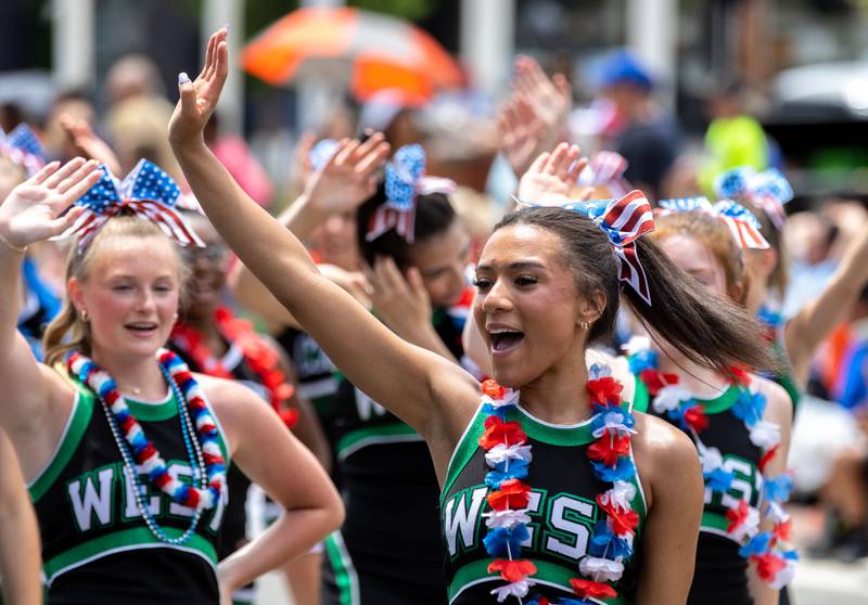 A Glenbard West High School cheerleader waves to the crowd during Glen Ellyn’s “4th of July Parade” on Friday, July 4, 2025.
