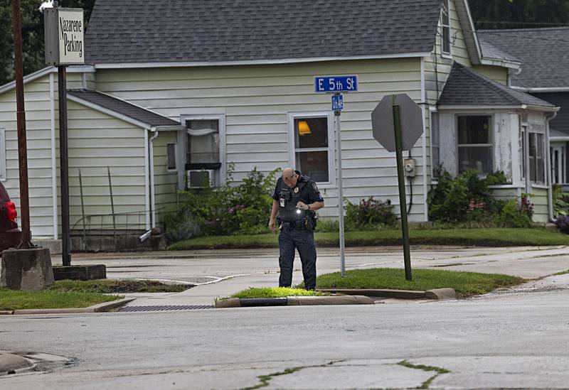 An officer looks for shell casings after at least eight shots were fired in a suspected shooting Tuesday night near the corner of East Fifth Street and 13th Avenue in Sterling.