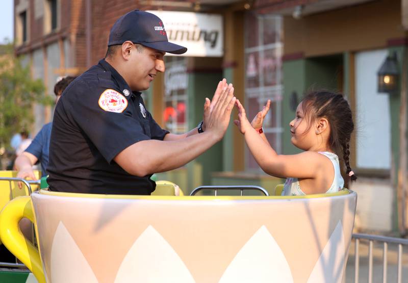 Genoa-Kingston firefighter Ulyses Parra high fives his daughter Sofia, 3, as they ride the tea cups at Genoa Days, Wednesday, June 7, 2023, in downtown Genoa. The festival continues through Saturday.