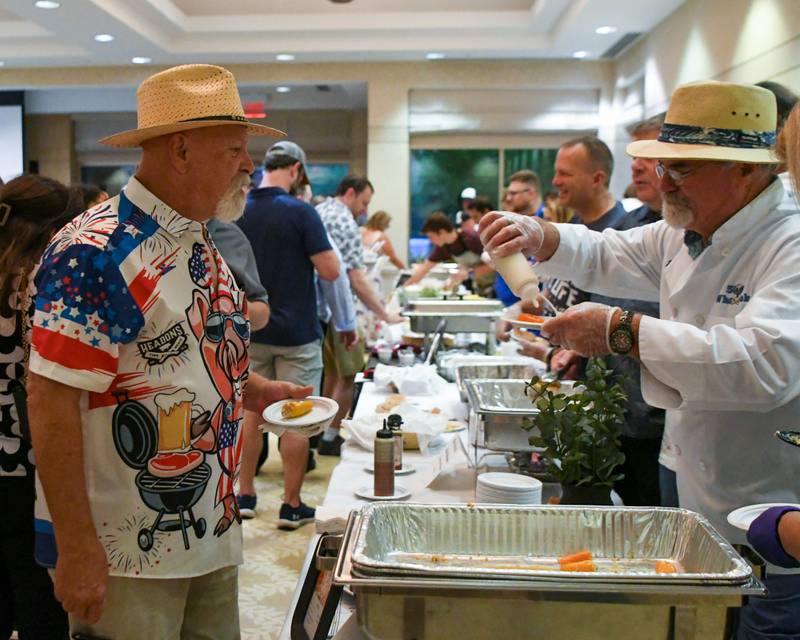 (From left) Bob Russman of Cortland talks with Brent Olson about his chicken bacon ranch poppers appetizer on Saturday, Aug. 9, 2025, during the 21st annual CASA DeKalb County's Men Who Cook fundraiser held at Northern Illinois University's Barsema Alumni and Visitors Center.