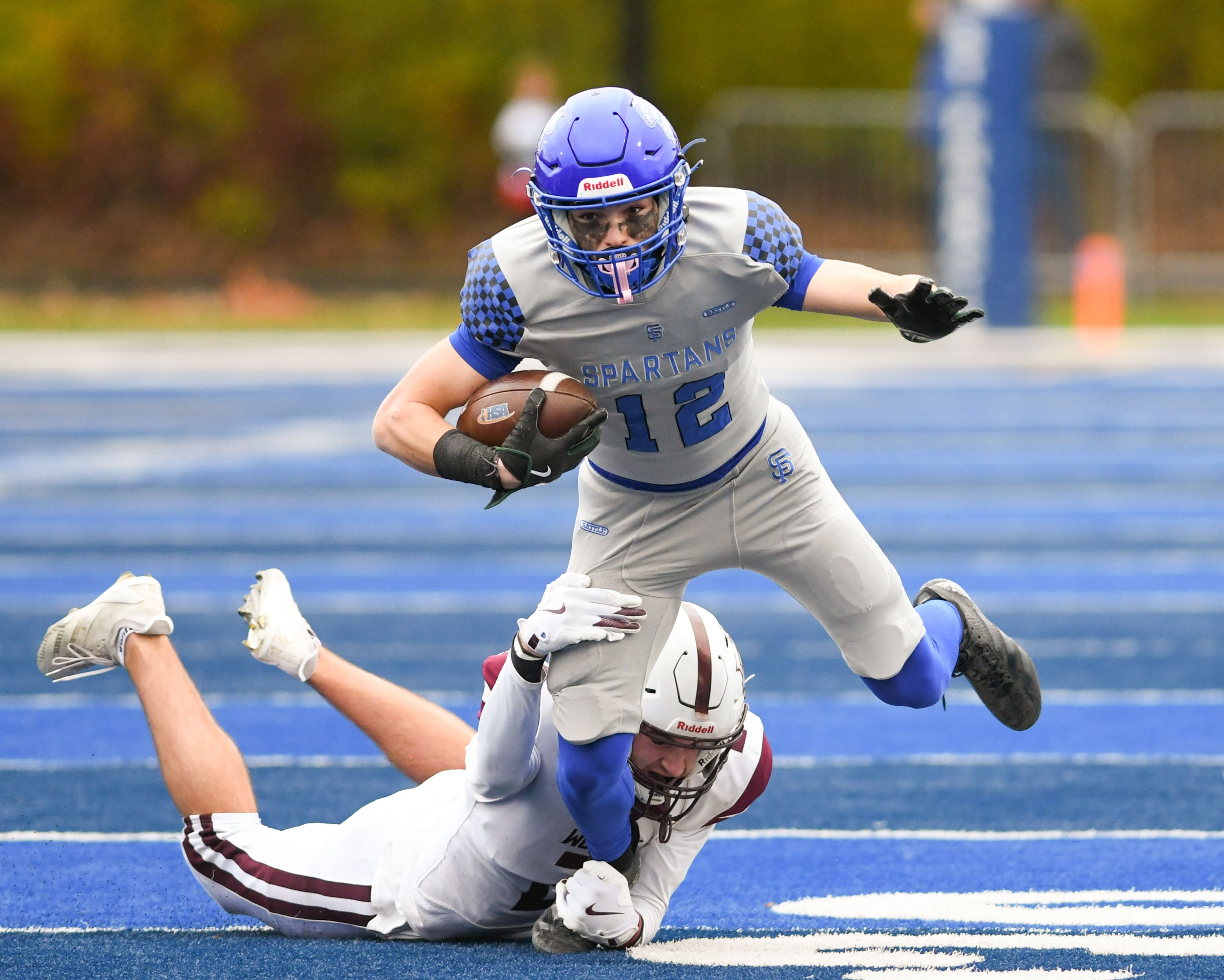 St. Francis's Dario Milivojevic (12) gains some yards before getting tripped up by Prairie Ridge's Logan Thennes (2) on Saturday Nov. 8, 2025, during the second round of the 5A playoff game held at St. Francis High School.