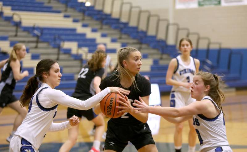 St. Charles North’s Reagan Sipla (center) tries to hang onto the ball under pressure from Geneva’s Peri Sweeney (left) and Caroline Madden (right) during a game at Geneva on Tuesday, Feb. 6, 2024.
