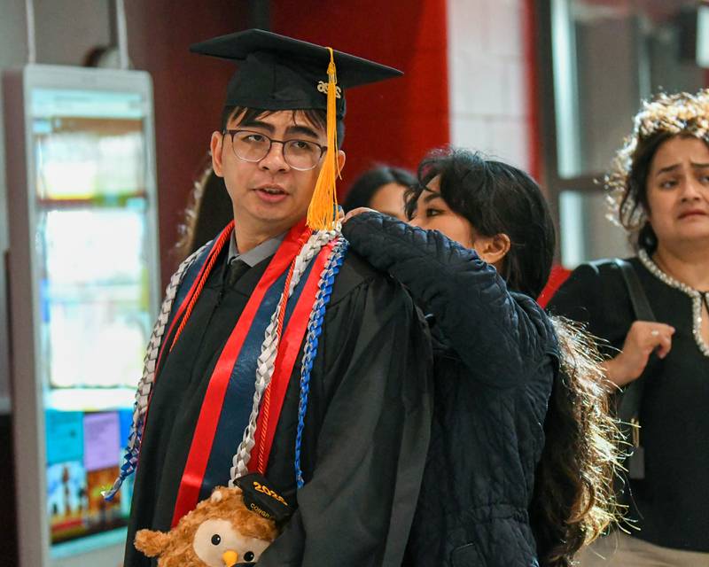 Angel Torio, right, a student at Northern Illinois University helps her boyfriend Brian Bounchaleun get ready before the start of the commencement ceremony on Saturday May 9, 2026, held at the Convocation Center in DeKalb.