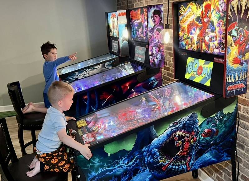 Rec Haus owner Erik Gilly's sons Ethan (behind), 6, and Jax (front), 4, play pinball in their home in St. Charles.