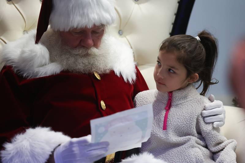Natalie Fabrizio, 7 years-old, watches as Santa reads her Christmas list at the Light Up the Holidays Festival and Parade in downtown Joliet.