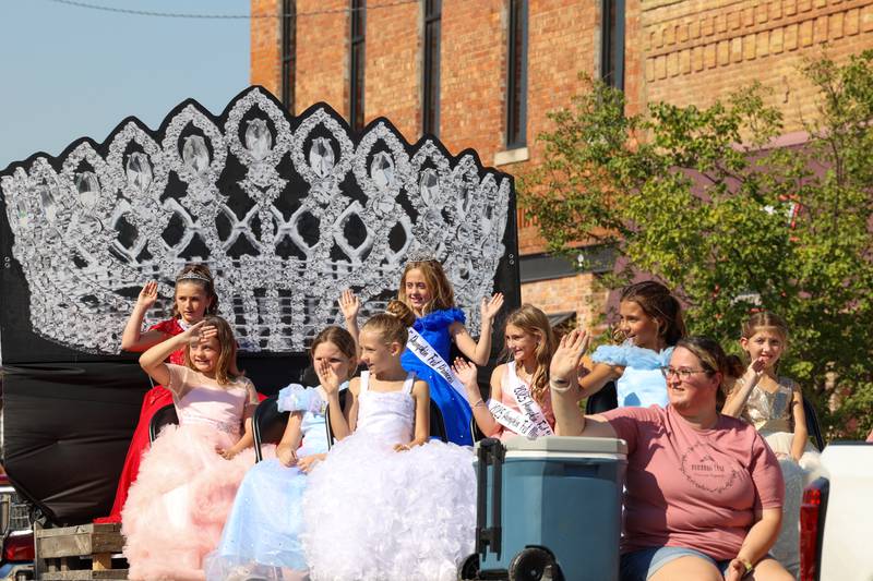 St. Anne Pumpkin Festival Princess Pageant contestands wave as they ride on a float in the Grand Pumpkin Parade during the St. Anne Pumpkin Festival on Saturday, Oct. 4, 2025. The 2025 St. Anne Pumpkin Fest Princess is Emma McFatridge and the Junior Miss is Vivianna Taylor, at top.