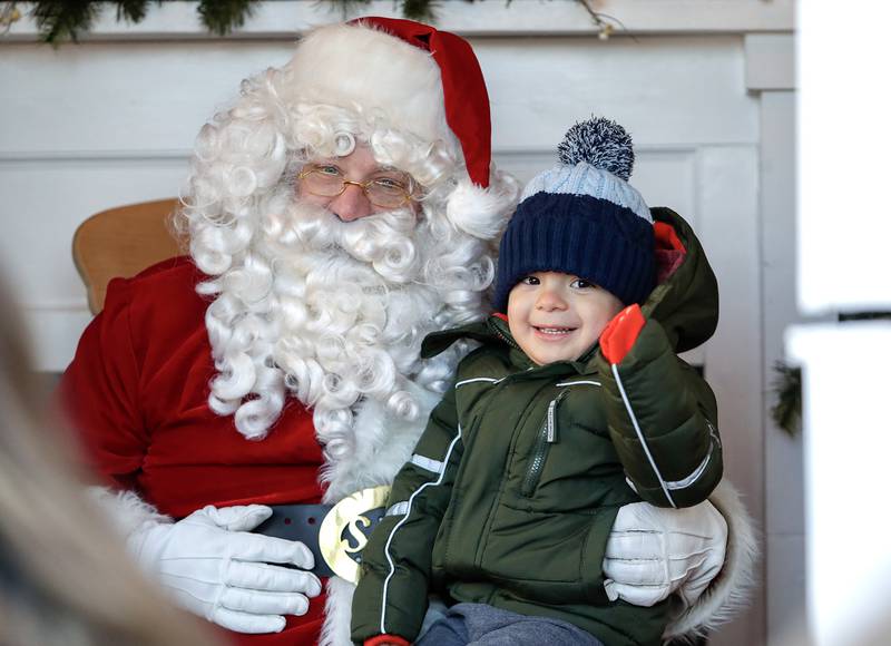 Nico Salinas, 3, of Lisle takes a photo with Santa Claus at the Gingerbread House in Downers Grove, Ill. on Sunday, Dec. 18, 2022.