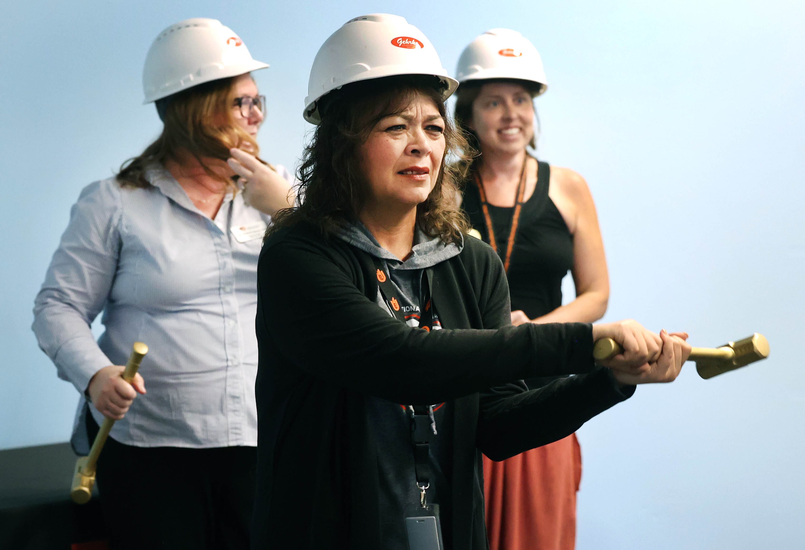 DeKalb School District 428 Superintendent Minerva Garcia-Sanchez gets loose before taking a ceremonial swing into the drywall Friday, Aug. 9, 2024, during the Beyond One Barb Transition Center Construction Kick-Off event at the new site at 530 Charter St. in DeKalb.