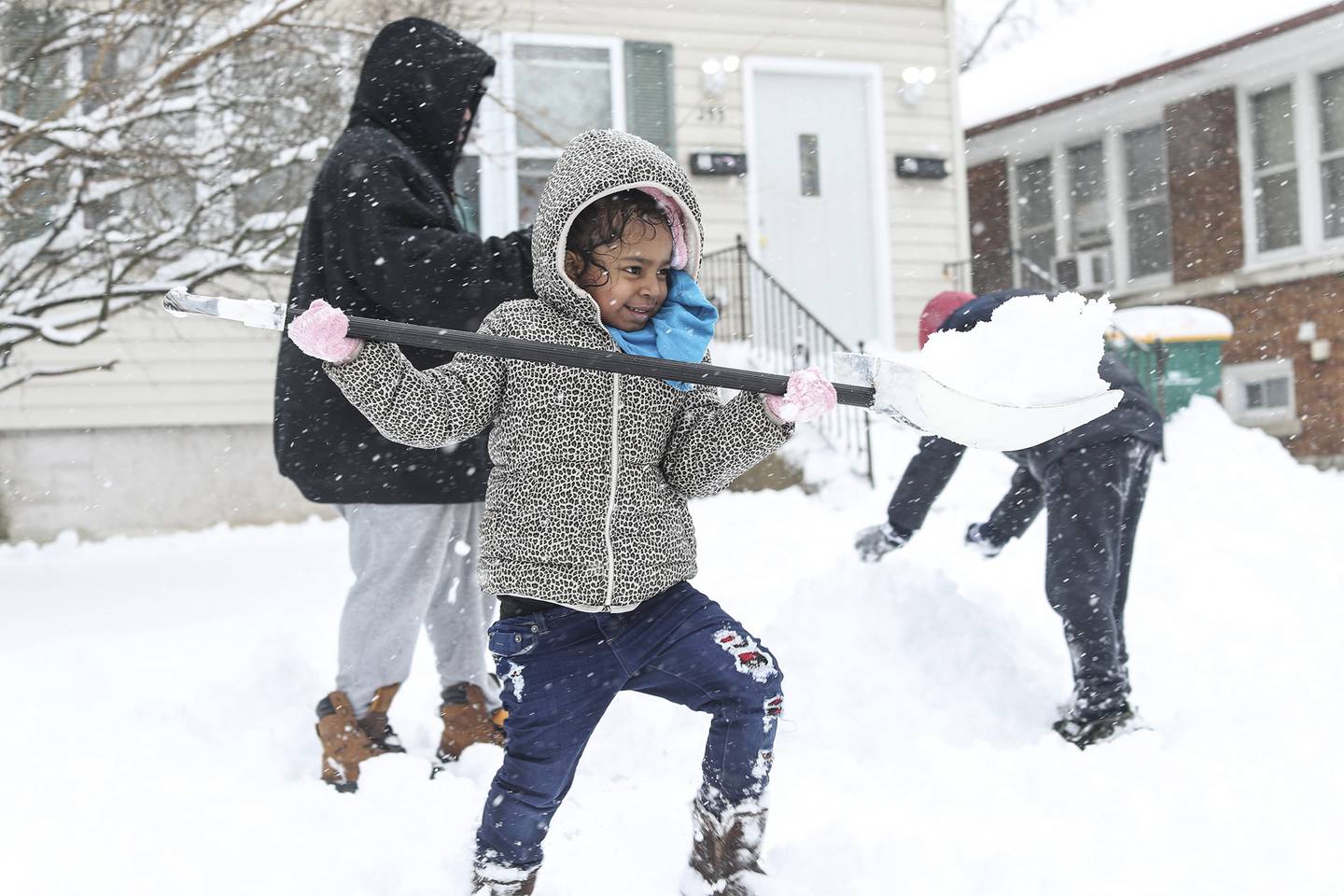 Amor Stevenson helps her family clear snow on Sunday, Jan. 31, 2021, in front of her family's home in Joliet, Ill. Nearly a foot of snow covered Will County overnight, resulting in fun for some and challenges for others.