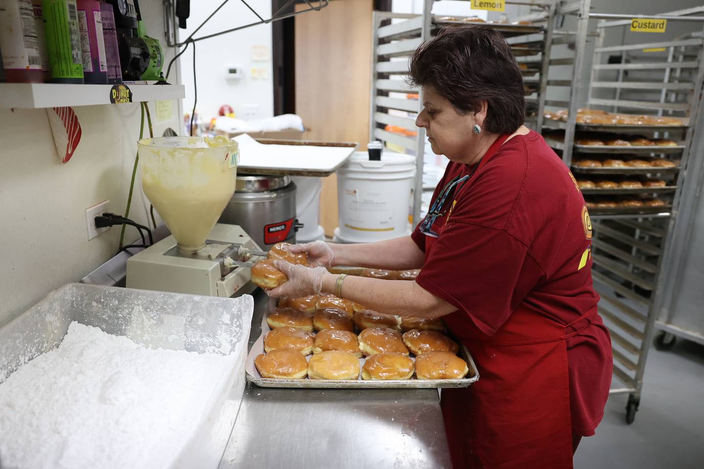 Susan Kuhnke fills a tray of paczki doughnuts with cheese. Donut Den has over 300 orders for the popular Polish doughnut. Monday, Feb. 28, 2022, in Joliet.