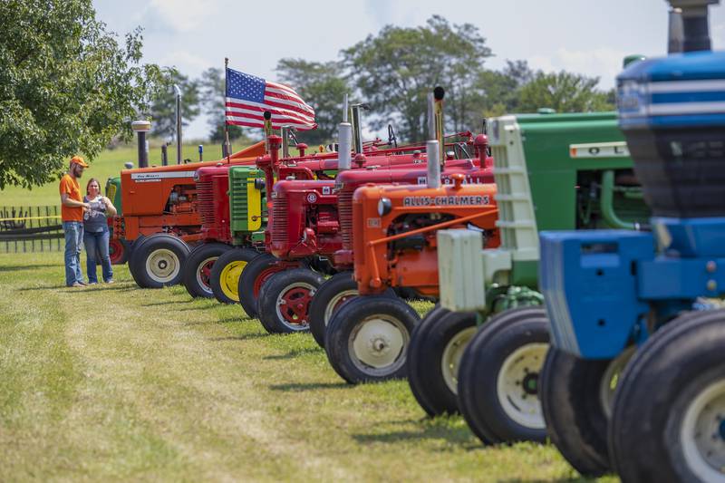 Andy and Emari Gustafson of Byron tour a line of antique tractors Saturday, Aug. 3, 2024, at the Living History Antique Equipment Association’s farm show in Franklin Grove. Once a year, club members showcase equipment from farming days of old with demonstrations of the tractors and their gear.