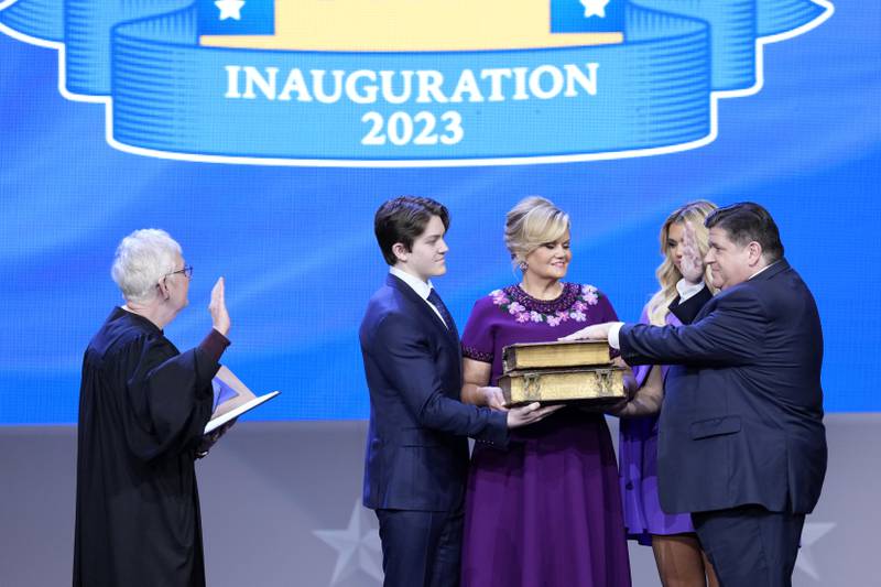 Illinois Gov. J.B. Pritzker, right, takes the office from Mary Jane Theis, Illinois Supreme Court Chief Justice as his wife M.K. Pritzker, son Don, daughter Teddi watch during ceremonies Monday, Jan. 9, 2023, in Springfield, Ill. (AP Photo/Charles Rex Arbogast)