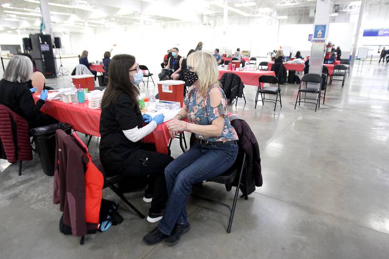 Maureen Bergeson of St. Charles (right) chats with Judith Zwart, a Kane County Health Department employee, before getting a COVID-19 vaccination at the county's first COVID-19 mass vaccination site on Friday, March 19, 2021. Bergeson and Zwart grew up together in St. Charles and attended St. Patrick's. The site is located in the former Sam's Club building at 501 N. Randall Road in Batavia. It will be open six days a week and is expected to serve 18,000 people per week to start.