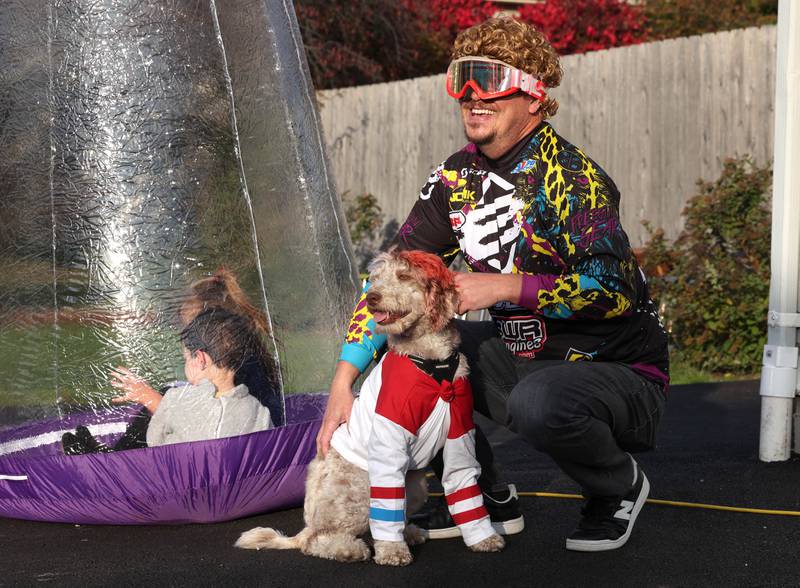 John Gillot and his dog Lucy, dressed as Harley Quinn, greet trick-or-treaters on Halloween, Friday, Oct. 31, 2025, in DeKalb.