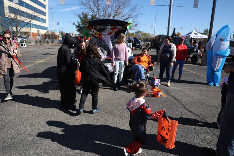 A family collects candy at one of the dozen of decorated vehicles at the Joliet Police Department Trunk-Or-Treat event on Saturday, Oct. 26, 2024 in Joliet.