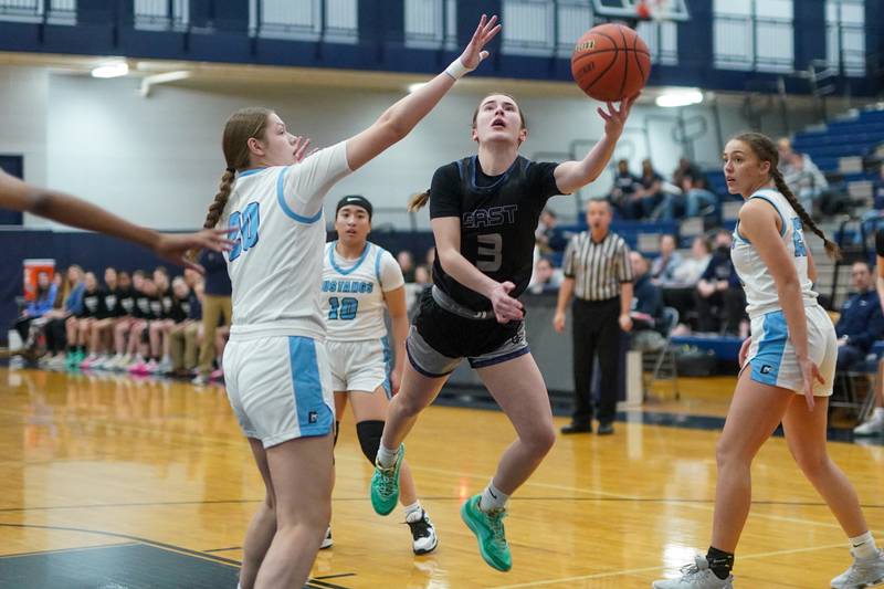 Oswego East's Maggie Lewandowski (3) drives to the basket against Downers Grove South's Megan Ganschow (20) during a 4A Oswego East Regional semifinal girls basketball game at Oswego East High School on Monday, Feb 12, 2024.