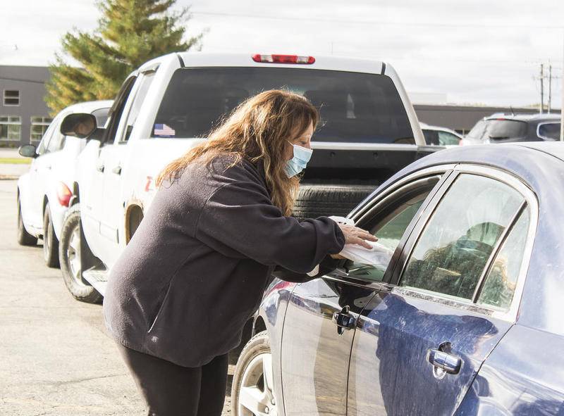 Kathy Bloomberg, from 160 Driving Academy, hands a bag full of job opportunities to a driver during the drive-thru job fair outside the Sauk Valley Food Bank in Sterling. NCI Works and the Sauk Valley Food Bank hosted the job fair.