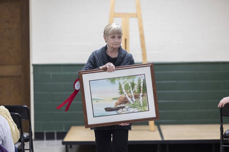 Phidian member Carolyn McKee-Freese displays a work by Betty Predmore Thursday, April 3, 2025, during the announcing of awards.