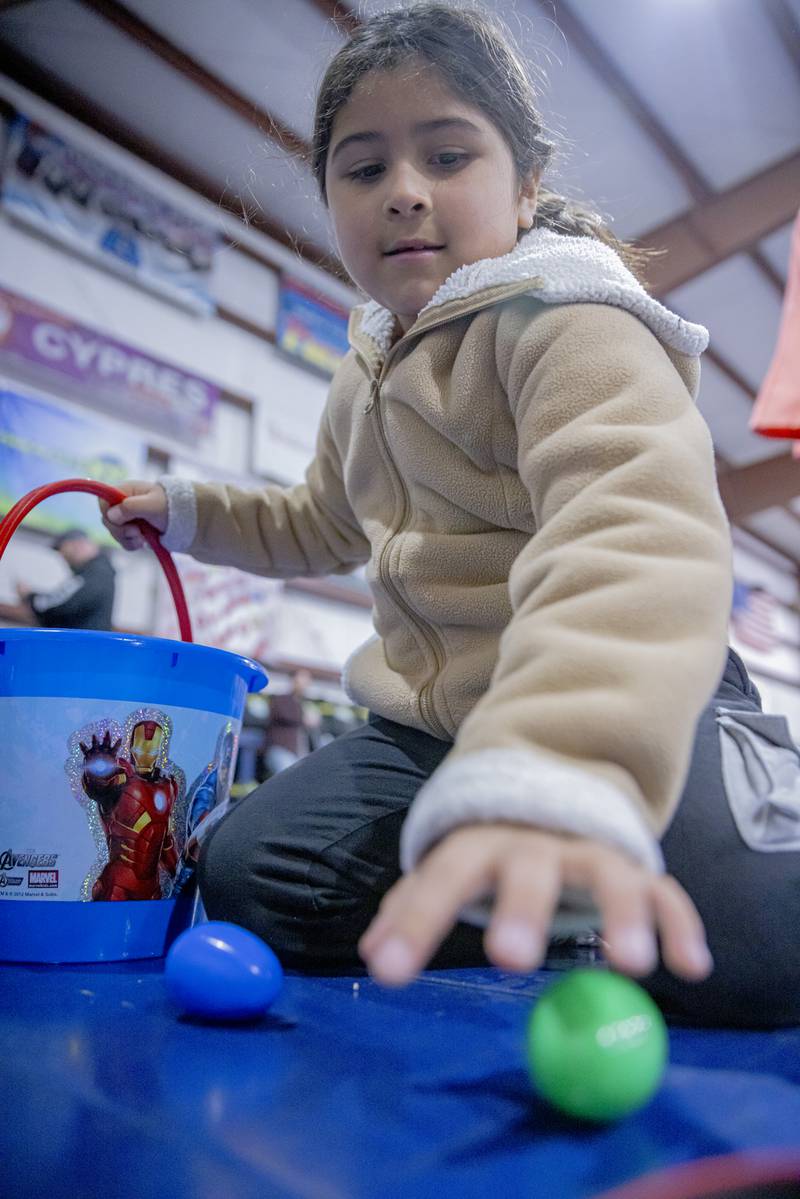 Jade Mumoz collects on of thousands of Easter eggs scattered around the hangar of Skydive Chicago on April 7, 2024. The eggs were divided up among different age groups for the kids safety.