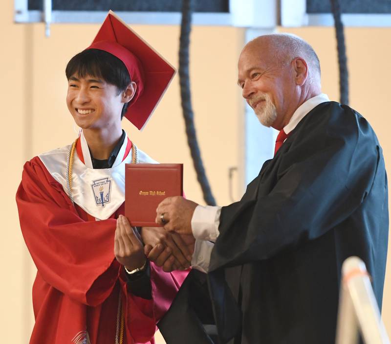 Oregon High School graduate Lux Tran receives his diploma from school board member Gary Schrimpsher during the Class of 2026 commencement ceremony at the Blackhawk Center in Oregon on Sunday, May 24, 2026.