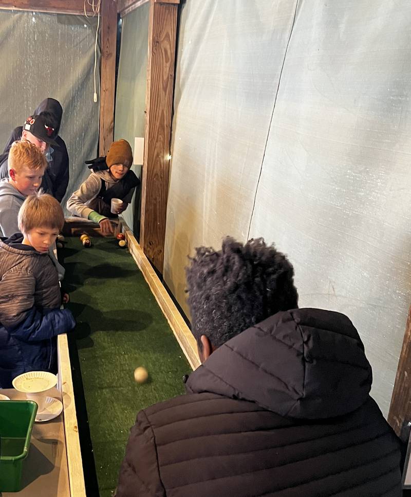 Keegan Johnson plans his next move in carpetball, while Grant Johnson, Jackson Floto, and Isaac Diveley watch during BEST School's trip to Echo Bluff Park in Spring Valley.