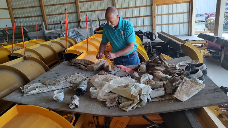 Bourbonnais Public Works Superintendent Terry Memenga sorts through items found in a time capsule buried during the village's centennial in 1975.