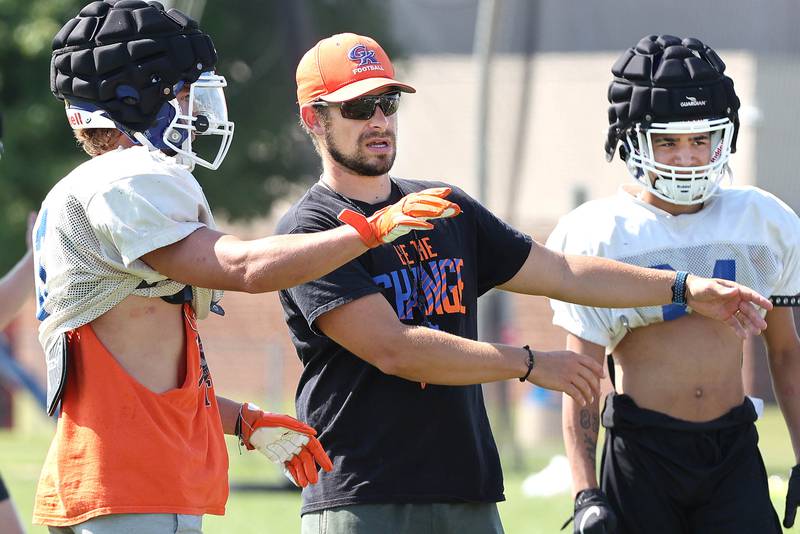 Genoa-Kingston head coach Cam Davekos talks to Brody Engel Wednesday, Aug.10, 2022, during practice at the school in Genoa.
