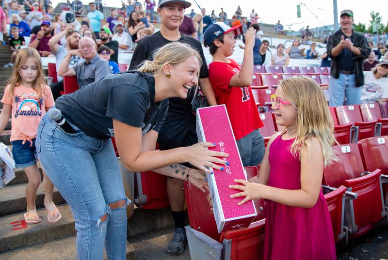 Cougars Crew member Kaylee Kowalski, left, gives Abby Flaherty, 6, of St. Charles an American Girl Doll during the Kane County Cougar's American Girl Night at Northwestern Medicine Field on Friday, July 29, 2022.