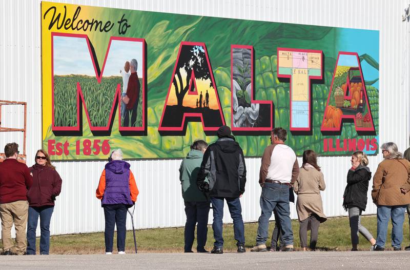 People view the new mural by Dixon artist Nora Balayti before the official ribbon cutting Wednesday, Oct. 19, 2022, on the north side of Route 38 in Malta. The mural, which spells out Malta in large capital letters, depicts the values of the town with themes of agriculture, family, community and growth.