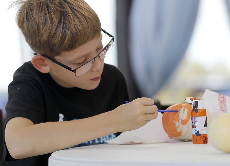 James Mitchel of Huntley, paints pumpkin during a stop on the McHenry County Farm Stroll on Sunday, Sept. 29, 2024, at Piscasaw Gardens in Harvard. The farm stroll, a self-guided tour of McHenry County’s family farms, featured farm tours, demonstrations and products for sale at eleven farms.