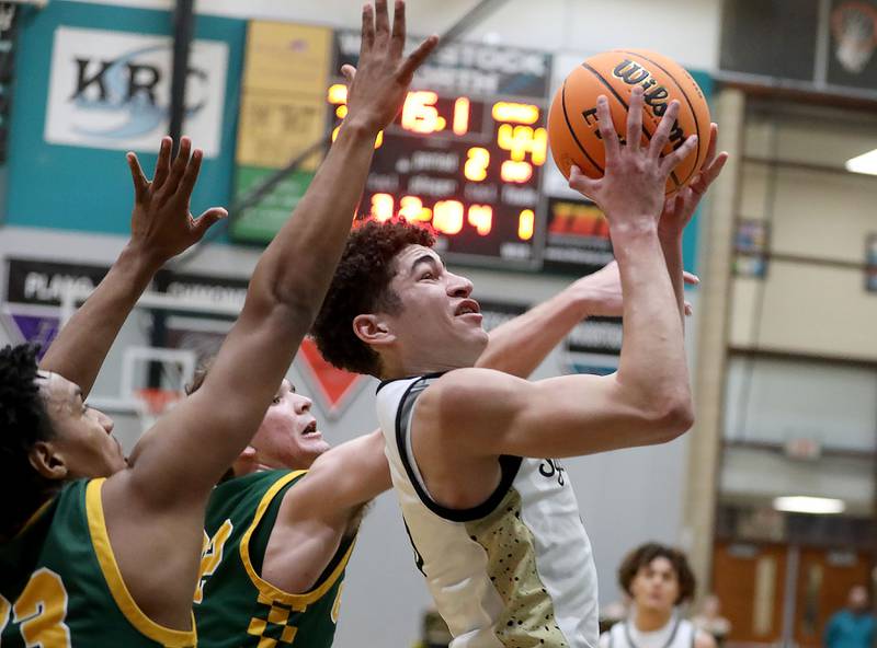 Sycamore's Marcus Johnson (right) drives between Crystal Lake South's David Mcfadden (left) and Nick Stowasser (center) during an IHSA Class 3A Woodstock North Sectional semifinal.basketball game on Wednesday, March 4, 2025, at Woodstock North High School.