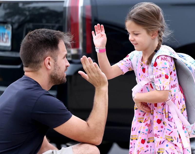 Kindergartener Adeline Russell high fives her dad Rob Thursday, Aug. 21, 2025, as she arrives for her first day of school at North Grove Elementary School in Sycamore.