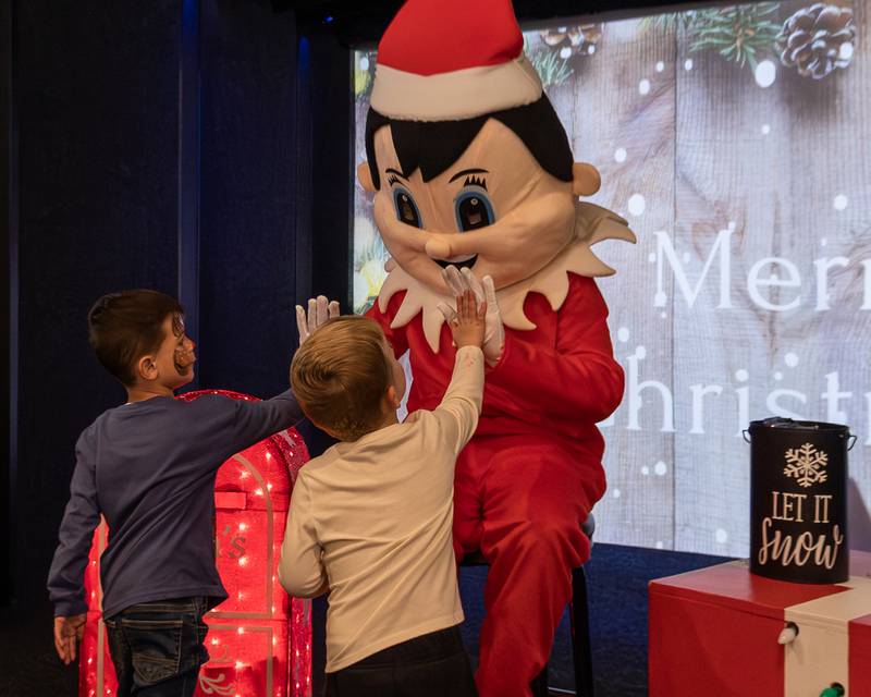 (from left) Levi Pyszka and Riley Waynick high-five Elf at the annual Christmas in the Valley on Saturday, November 15, 2025 at the Tee Box in Spring Valley.