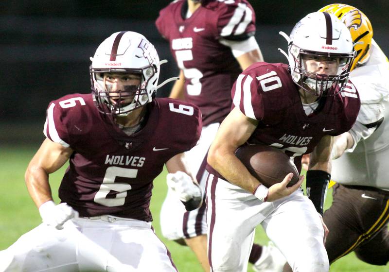 Prairie Ridge’s Jack Finn, right, runs the ball as Luke Vanderwiel, left, prepares to block against Jacobs in varsity football at Crystal Lake Friday night. Prairie Ridge won 6-0.