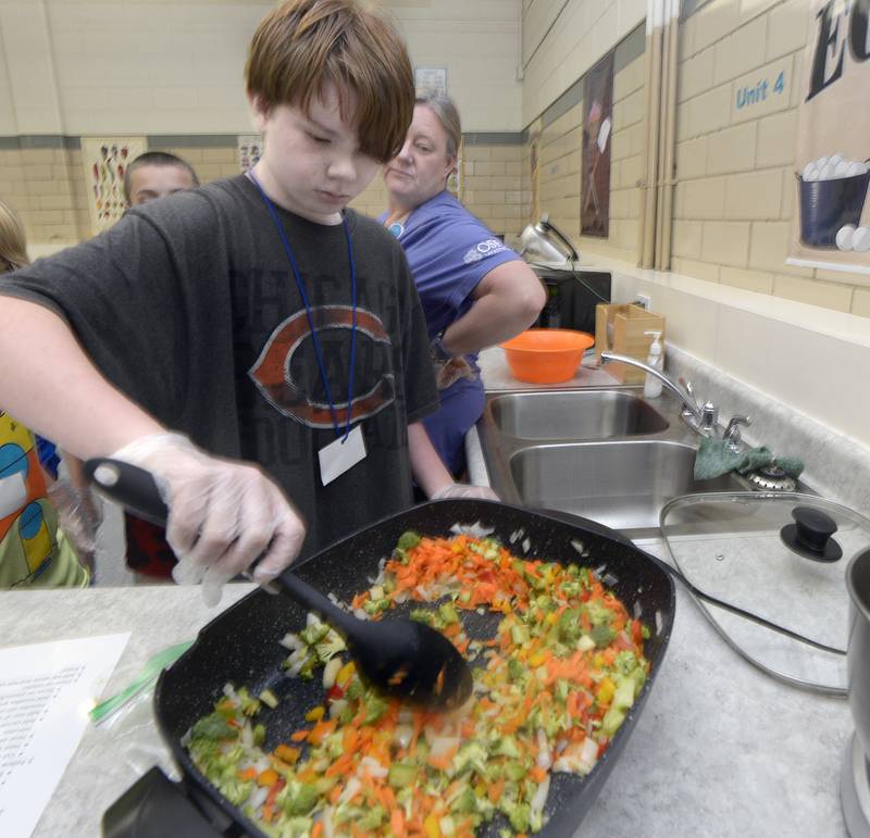 Caelan Jenkins works to stir fry vegetables Wednesday at Northlawn Junior High in Streator during the Illinois Junior Chefs program.