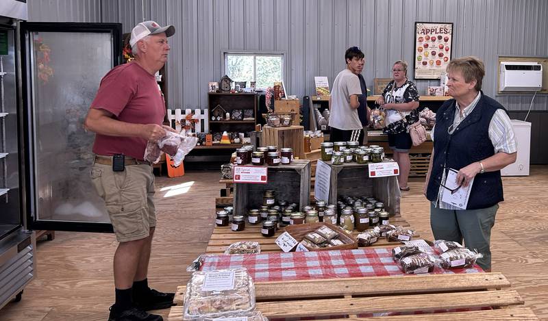 Jeff Warren (left) owner of  BerryView Orchard, 7504 W. Midtown Road, Mt. Morris, waits on a customer Saturday, Sept. 27, 2025 during the sixth annual Back Roads Market.