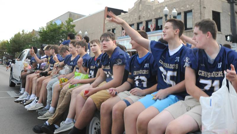 The Marquette Academy High football team toss treats to those along LaSalle St in Ottawa Wednesday for the school’s Homecoming parade.