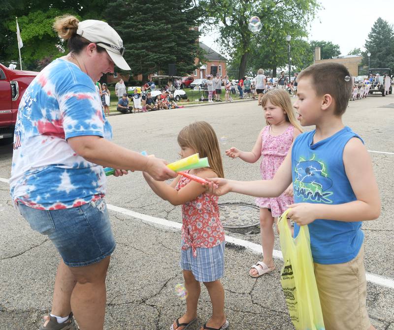 Lisa Hinrichs with the Blackhawk Crossing 4-H Cub hands out flavored ice treats to Owen, Stella and Elizabeth Newcomer of Oregon during the Let Freedom Ring Grand Parade on July 4.